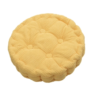 Detail of yellow round corduroy chair cushion showing thick texture and tufted quilting