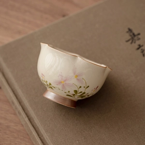 Hand-painted ceramic tea cup with floral motifs and elegant scalloped rim design