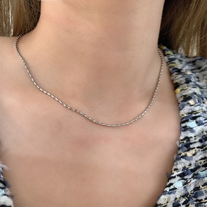 Detailed view of ultra-thin 18K gold plated titanium rice bead necklace on model neck