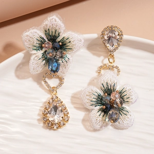Détail de boucles d'oreilles asymétriques en fleurs de tissu et strass goutte