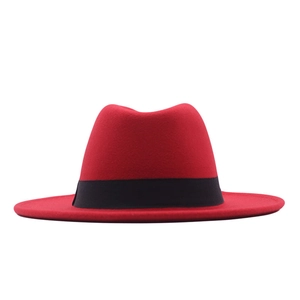 Detail view of a red wool felt wide brim fedora hat with a stylish black ribbon band