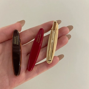 Vue détaillée de trois barrettes ovales en acétate en tons écaille, rouge et crème