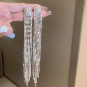 Macro shot of long gold tassel earrings with zircon leaf design and crystal fringe