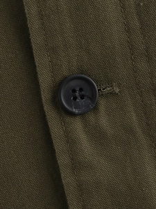 Macro shot of olive green canvas jacket fabric with black four-hole button detail