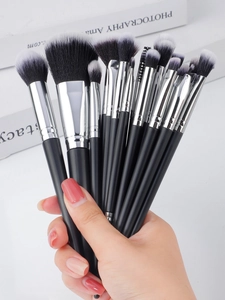 Close-up of model holding a 20-piece professional makeup brush set with black handles