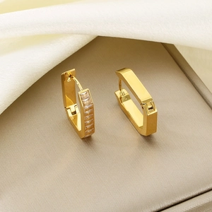 Macro shot of gold geometric earrings with rectangle cubic zirconia and polished finish