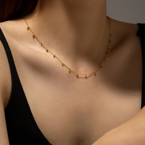 Elegant gold choker necklace with colorful zircon beads worn on a female model's collarbone