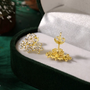 Macro shot of gold flower earrings with clear zircon stones on a velvet box