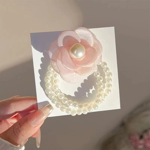 Close-up of pink fabric camellia hair tie with triple-layer white pearl beads