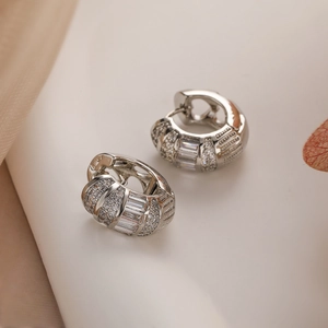Close-up of silver-plated hoop earrings featuring baguette and round zircon stones