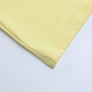 Close-up of double-needle stitching on the hem of a pale yellow evening dress fabric