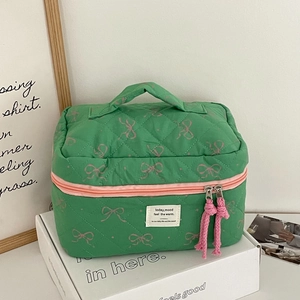 Detail of green quilted makeup bag with pink bow pattern and woven zipper puller