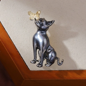 Macro detail of retro baroque cat brooch with golden butterfly on beige fabric background
