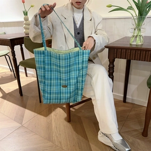 Lifestyle shot of large checkered canvas tote bag in blue and green in a cafe