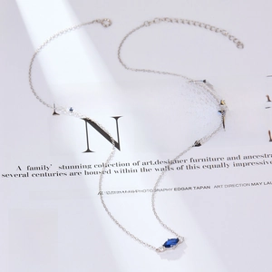 Macro shot of S925 sterling silver necklace with blue marquise stone on magazine