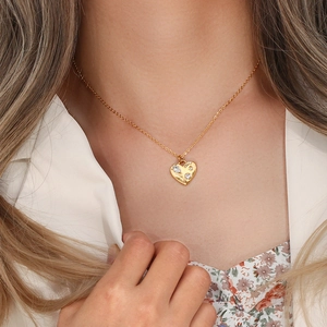 Close-up of golden heart pendant necklace with shimmering crystals on female model