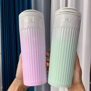Close-up of pink and green insulated coffee cups with vertical stripe texture held by hand