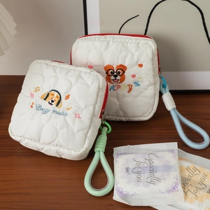Détail d'une trousse de maquillage matelassée avec broderie chien et dragonne colorée.