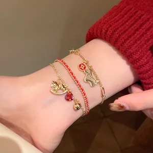 Close-up of red cord bracelet with gold pony pendant and zircon accents on a wrist