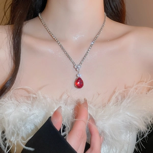Detail view of water drop red zircon necklace on model with elegant feather outfit