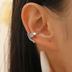 Macro detail of vintage silver dragon ear cuff with intricate scale textures on ear cartilage