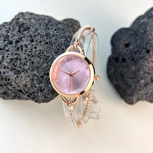 Detail of rose gold bracelet watch featuring a pink gradient dial and diamond accents