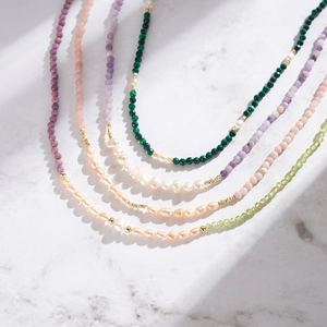 Handcrafted malachite and freshwater pearl necklace set on marble background