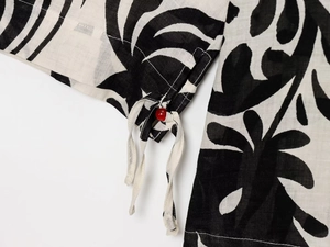 Detailed macro view of black and white print fabric with red bead and drawstring ties