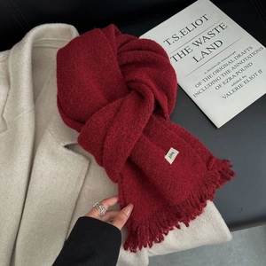 Détail de l'écharpe à carreaux rouge avec franges et étiquette sur manteau beige