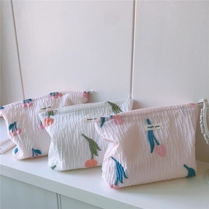 Détails de broderies tulipes et cerises sur des trousses de maquillage en tissu gaufré