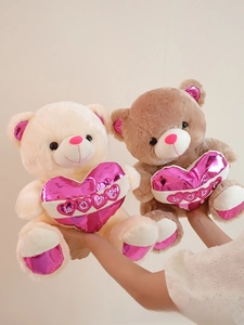 Close-up of plush teddy bears holding shiny pink hearts with LOVE embroidery