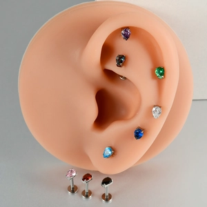 Detail view of colorful teardrop zircon studs displayed on a silicone ear model