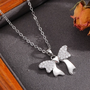 Close-up of bowknot necklace with zircon inlay on velvet cushion inside a jewelry box