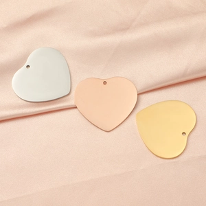Three polished heart-shaped pendants in gold, silver, and rose gold on pink silk fabric