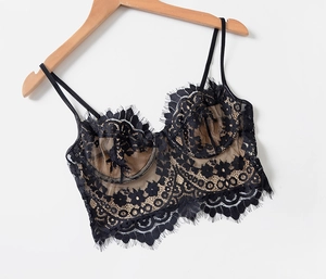 Close-up of black eyelash lace bralette with sheer mesh lining on a wooden hanger