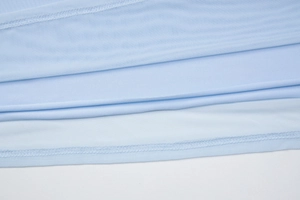 Detailed close-up of light blue knitted fabric texture and precise stitching on the dress