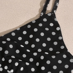 Detail of the black mesh fabric featuring white polka dots and delicate thin straps