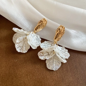Detail of petal tassel earrings with gold irregular hammer finish and silver textures
