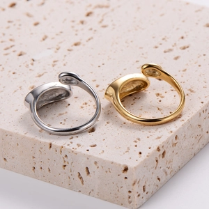 Minimalist gold and silver adjustable rings displayed on a textured stone pedestal