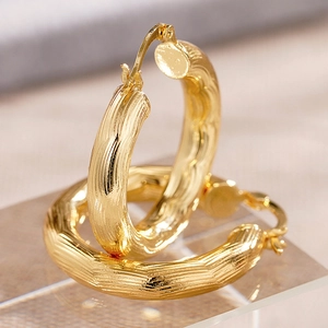 Nahaufnahme der dicken goldenen Creolen mit gerippter Oberfläche und Hochglanz-Finish