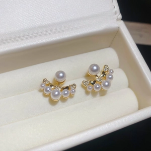 Detail view of fan-shaped pearl earrings with gold base and zircon accents in a jewelry box