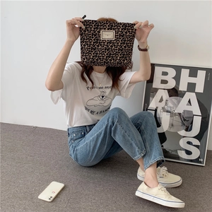 Leopard print canvas clutch styled with denim and sneakers in a casual lifestyle setting