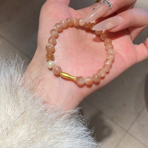 Elegant sunstone bead bracelet with white pearl and gold fish charm on wrist