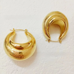 Détail de boucles d'oreilles créoles dorées avec motif peau de serpent et finition polie