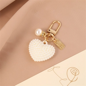 Detail of a gold pearl heart keychain with an engraved I wish you happy plate