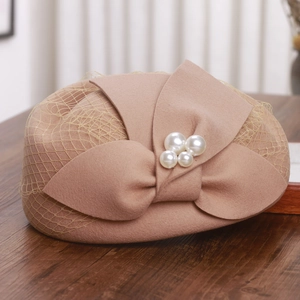 Detail of wool pillbox hat featuring mesh veil and bow with pearl accents