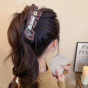 Détail d'une pince à cheveux en tissu écossais marron avec bouton vintage et étiquette