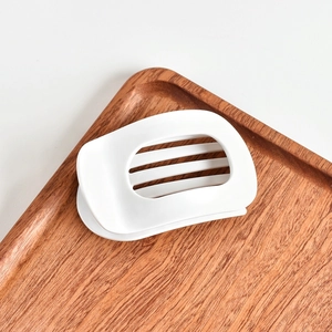 Close-up of minimalist cream white acetate hair claw with elegant hollow stripe design