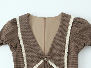 Detailed view of plaid dress collar with cream lace trim and delicate bow tie detail