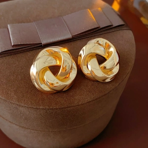 Gros plan de boucles d'oreilles dorées nouées sur un coffret à bijoux en velours brun